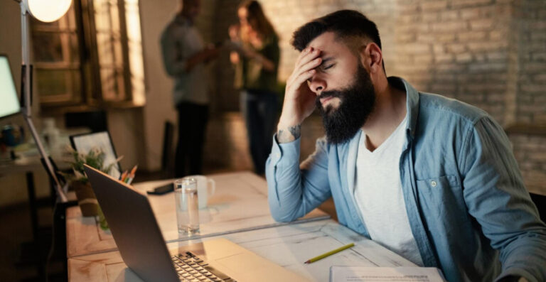 Empreendedor lidando com os desafios econômicos na gestão empresarial, demonstrando preocupação em seu ambiente de trabalho.