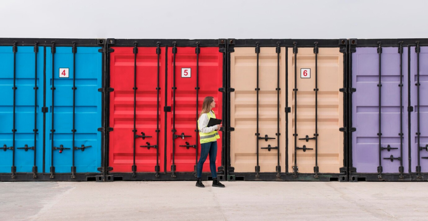 Mulher caminhando em frente a contêineres coloridos, representando operações de importação e logística em Santa Catarina.